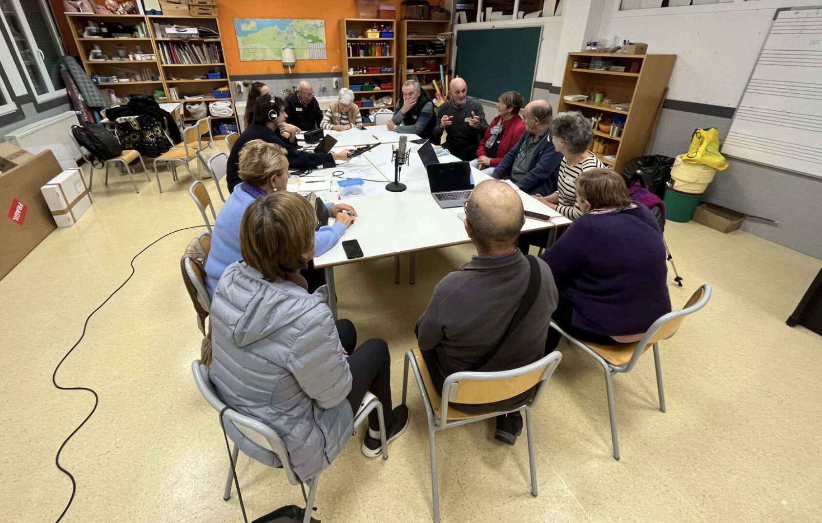Personas mayores alrededor de una mesa con micrófonos.