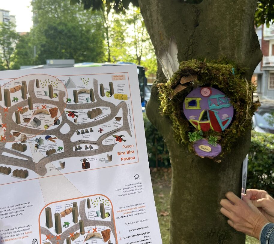 En esta imagen se ve de primer plano un mapa para guiar el primer paseo Bira Bira y por detrás una caseta en el árbol.